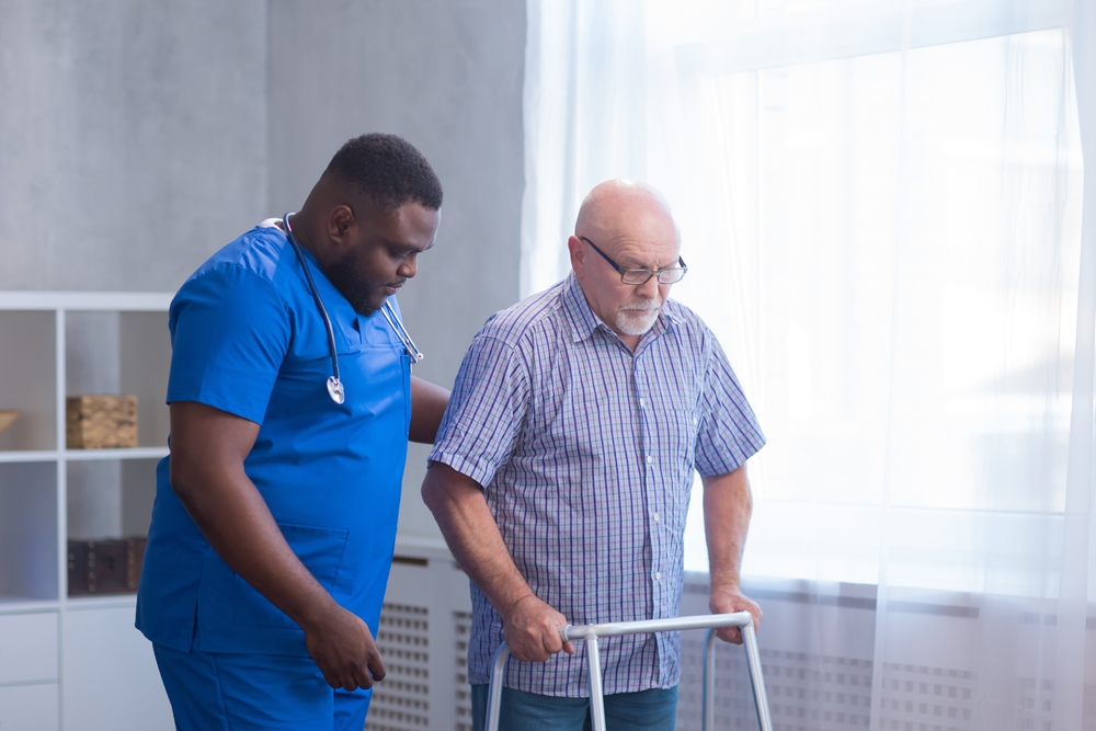Caregiver helping elderly client with mobility assistance