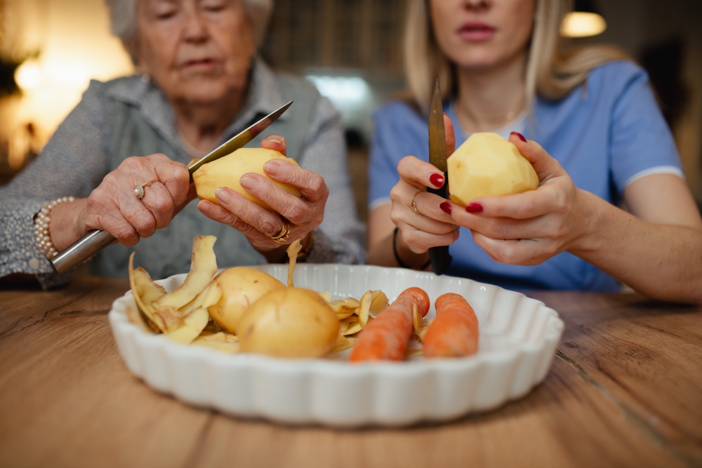 Caregiver helping elderly client prepare food